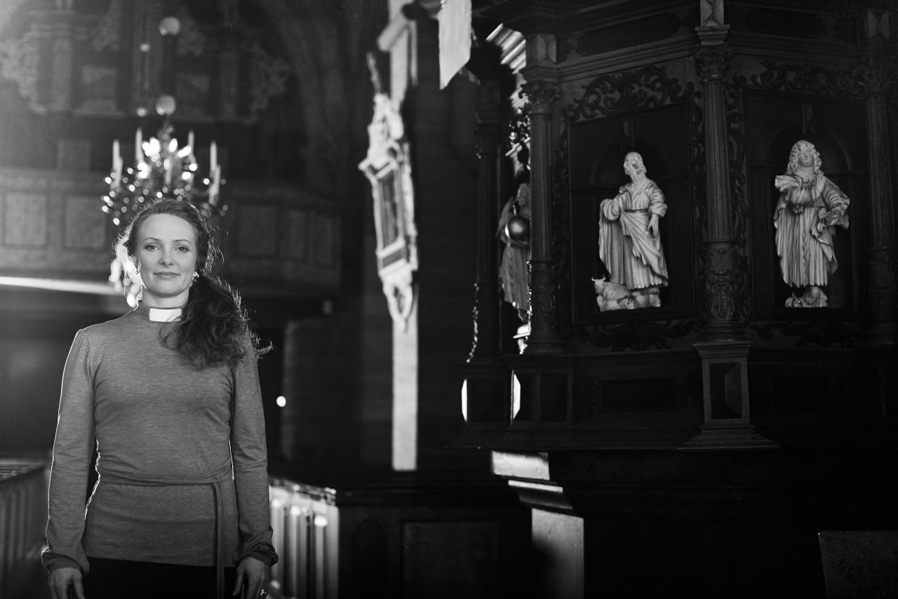 Svartvitt porträtt av en kvinna i ett kyrkorum.