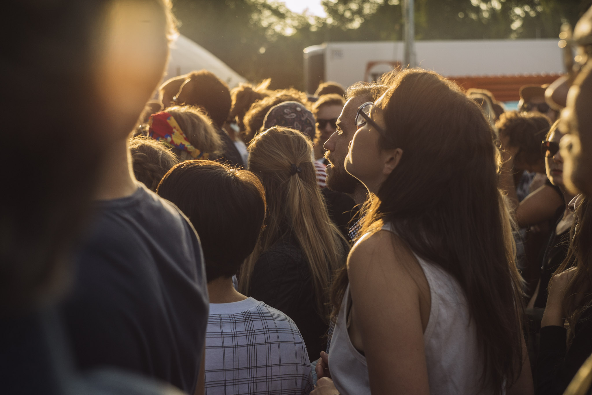En kvinna står i en konsertpublik med varmt ljus över ansiktet.