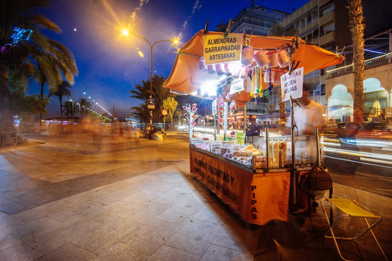 A small orange kiosk glows beside the street as traffic passes.