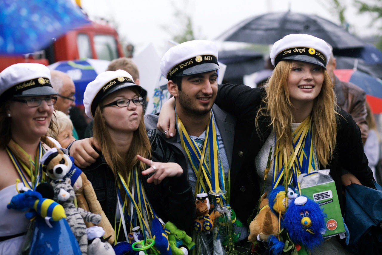 Unga vänner med studentmössor står tillsammans i folkvimlet.