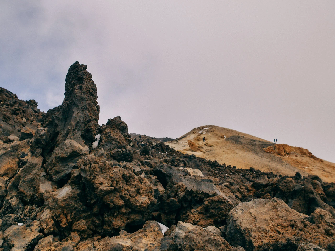 Mörka spetsiga klippor bryter upp ett öppet vulkaniskt landskap.