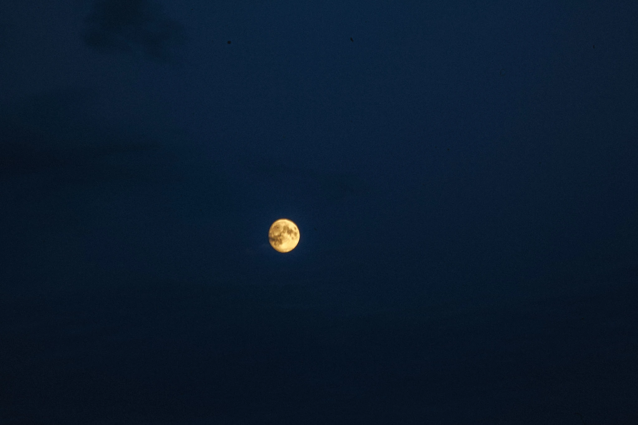 A small yellow moon in a deep blue sky.