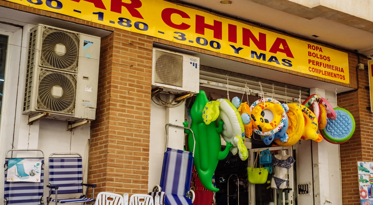 Colourful swimming rings hang outside a small shop beneath a yellow and red sign.