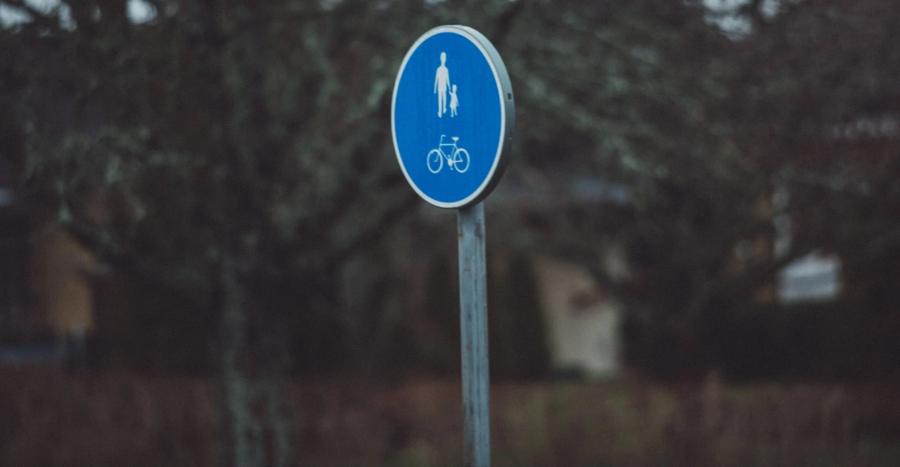A blue pedestrian and bicycle sign against a dark background.