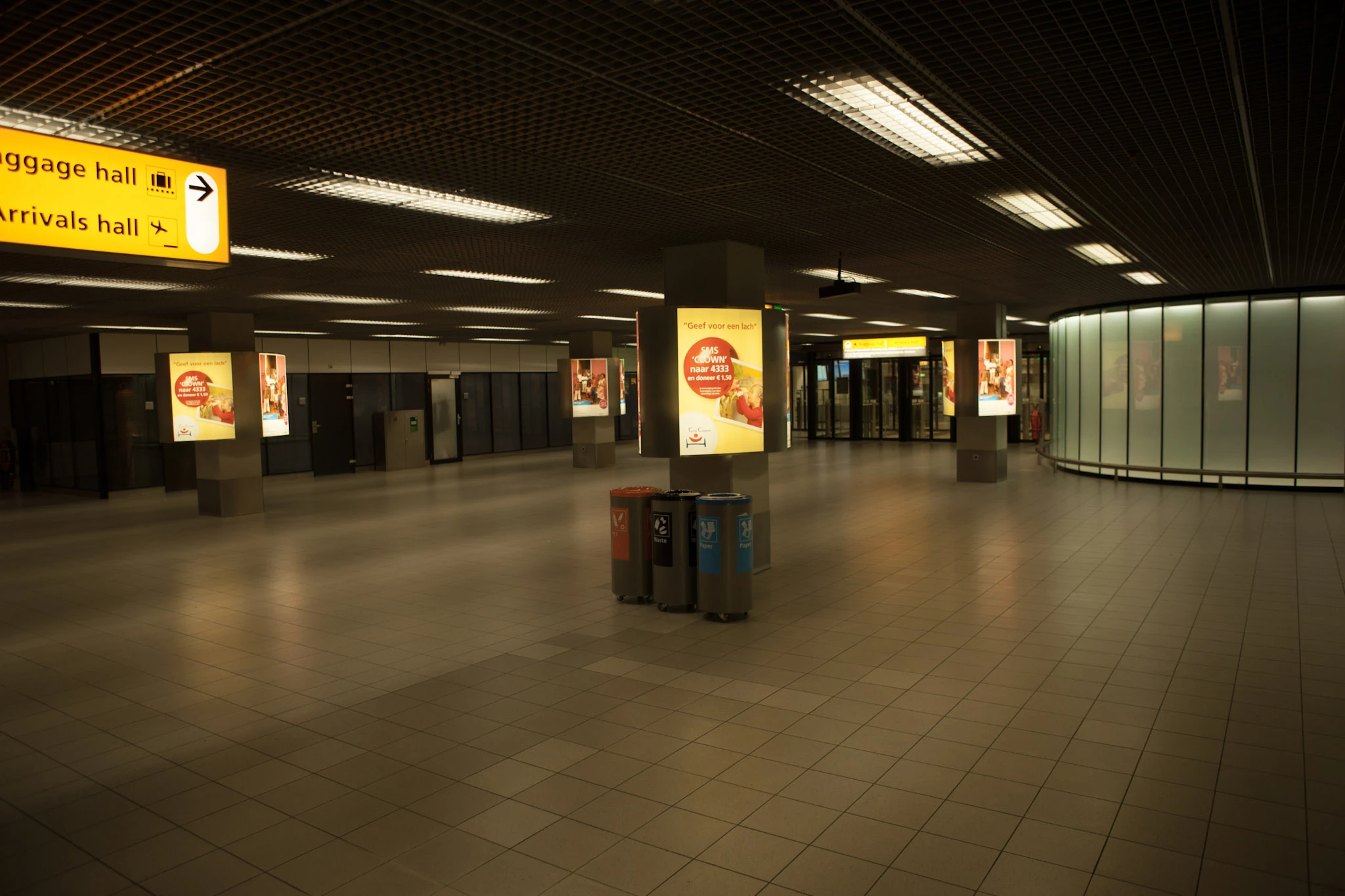 En nästan tom terminalhall med gula informationsskyltar.