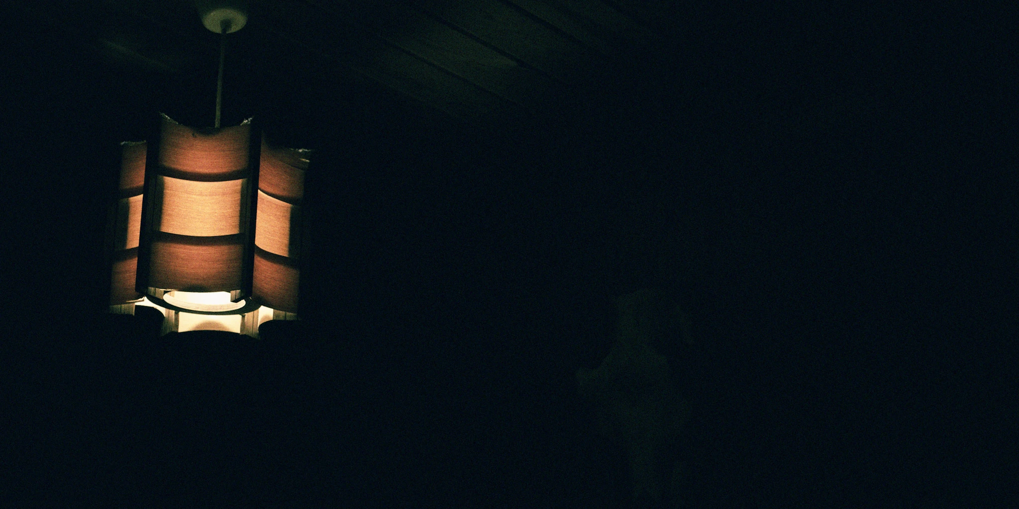 A single warm lamp in an almost completely dark room.