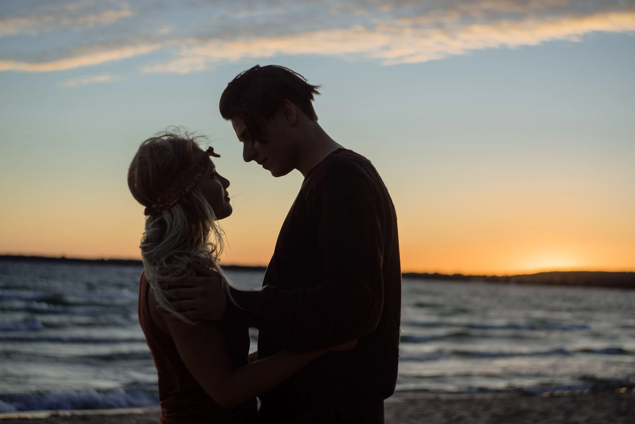 Två personer blir silhuetter mot solnedgången på stranden.