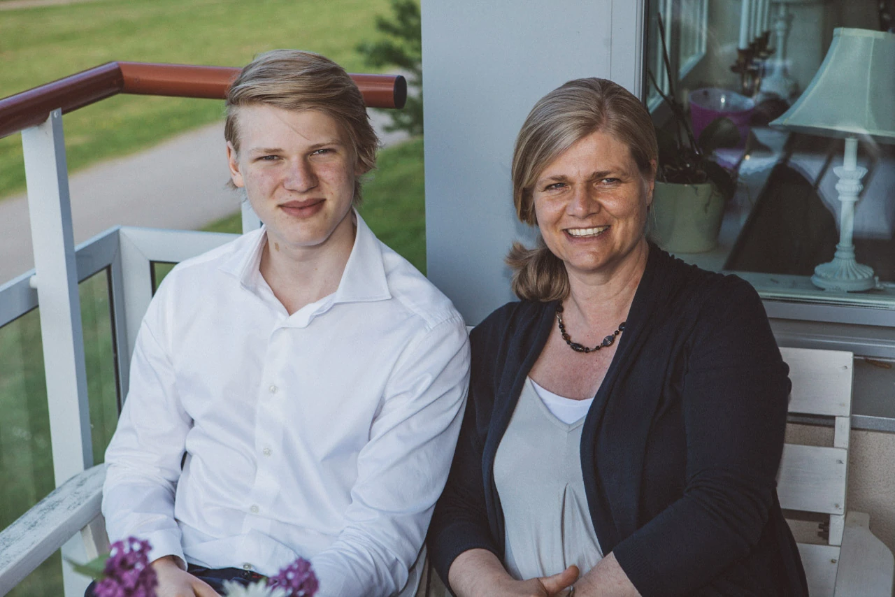 En ung man och en äldre kvinna sitter tillsammans framför kameran.