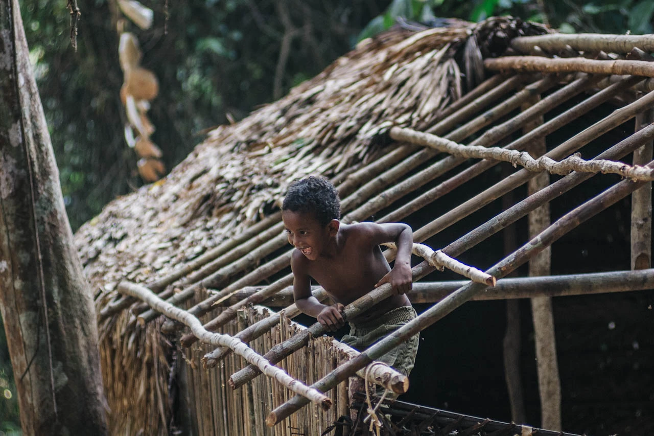 A person works among the wooden poles of a roof under construction.