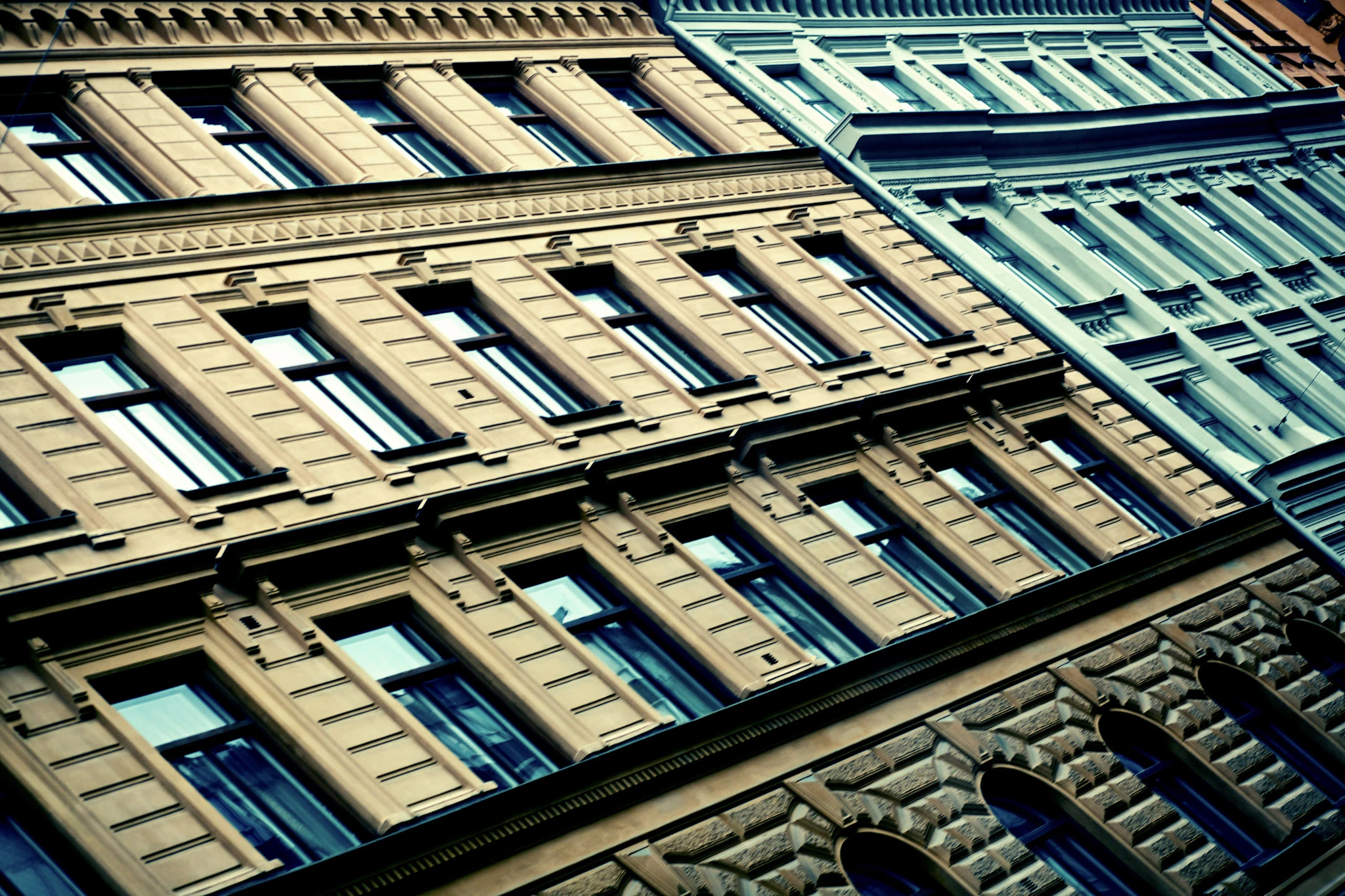 Diagonal rows of windows and ornate facade details in yellow and blue-green.