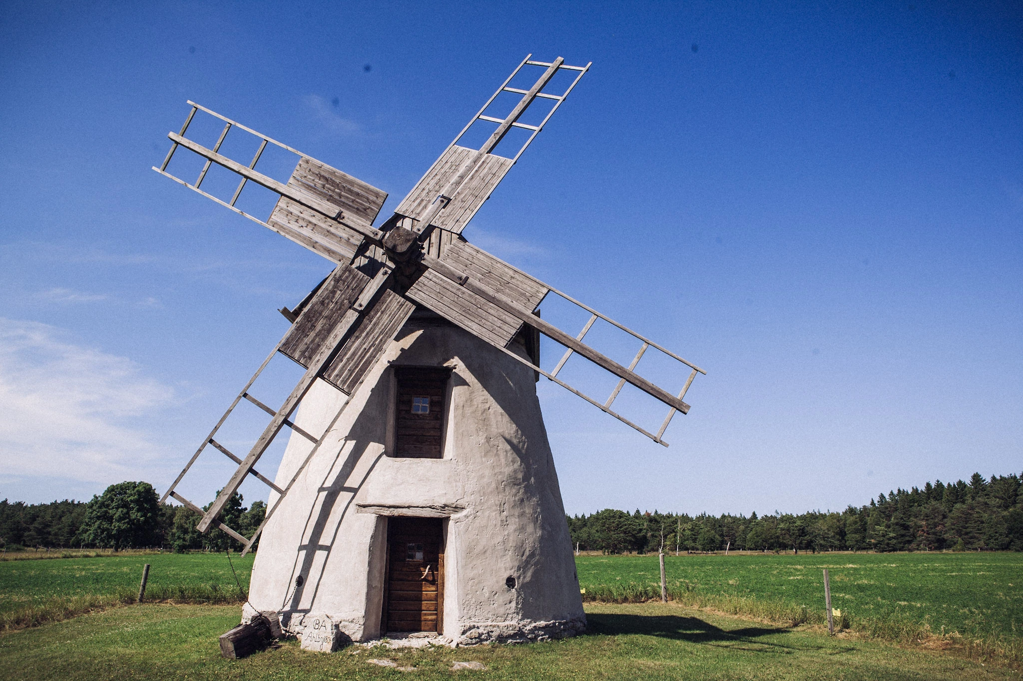 A white windmill in a field beneath a blue sky.