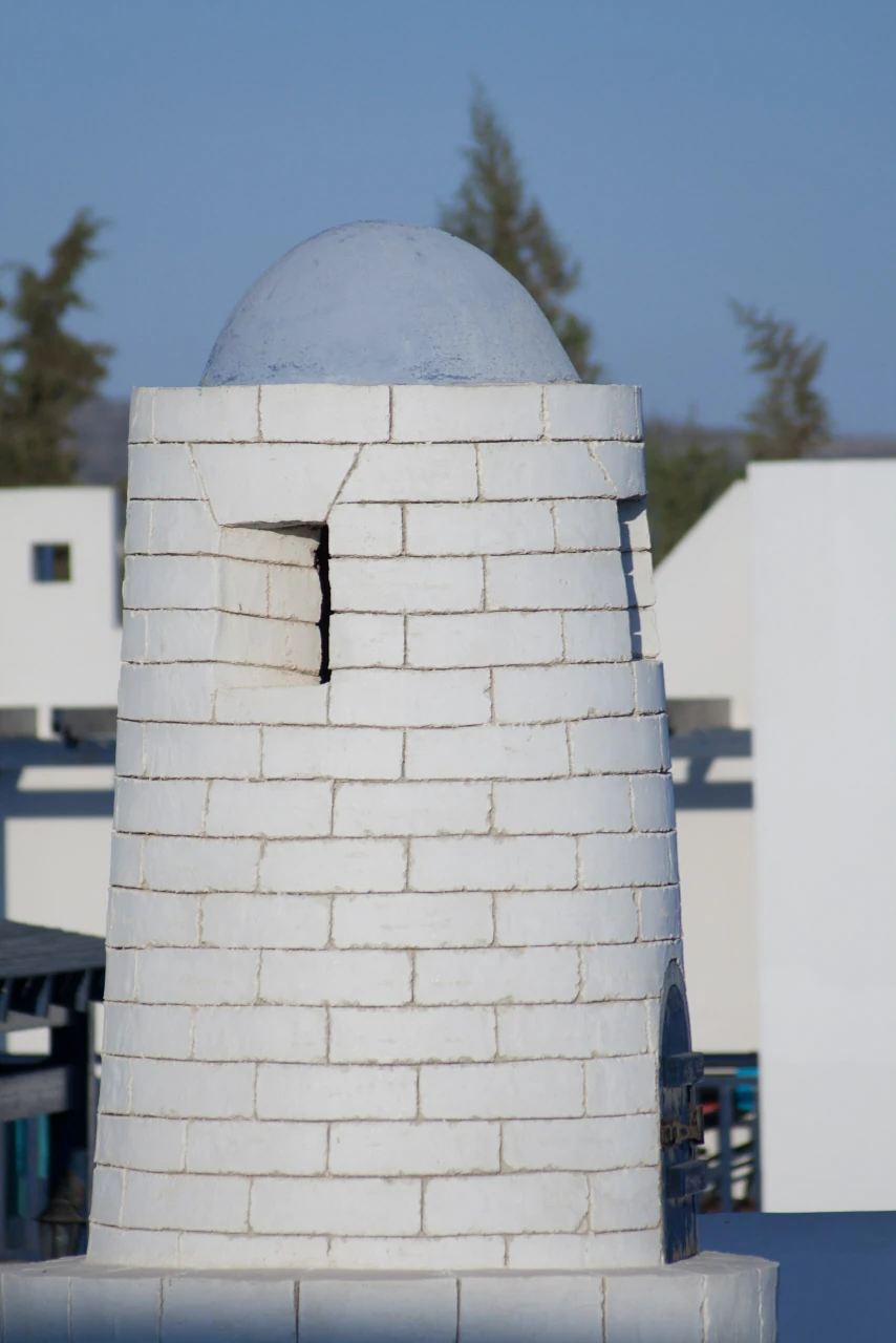 A round white block-built structure with a low domed roof beneath a blue sky.