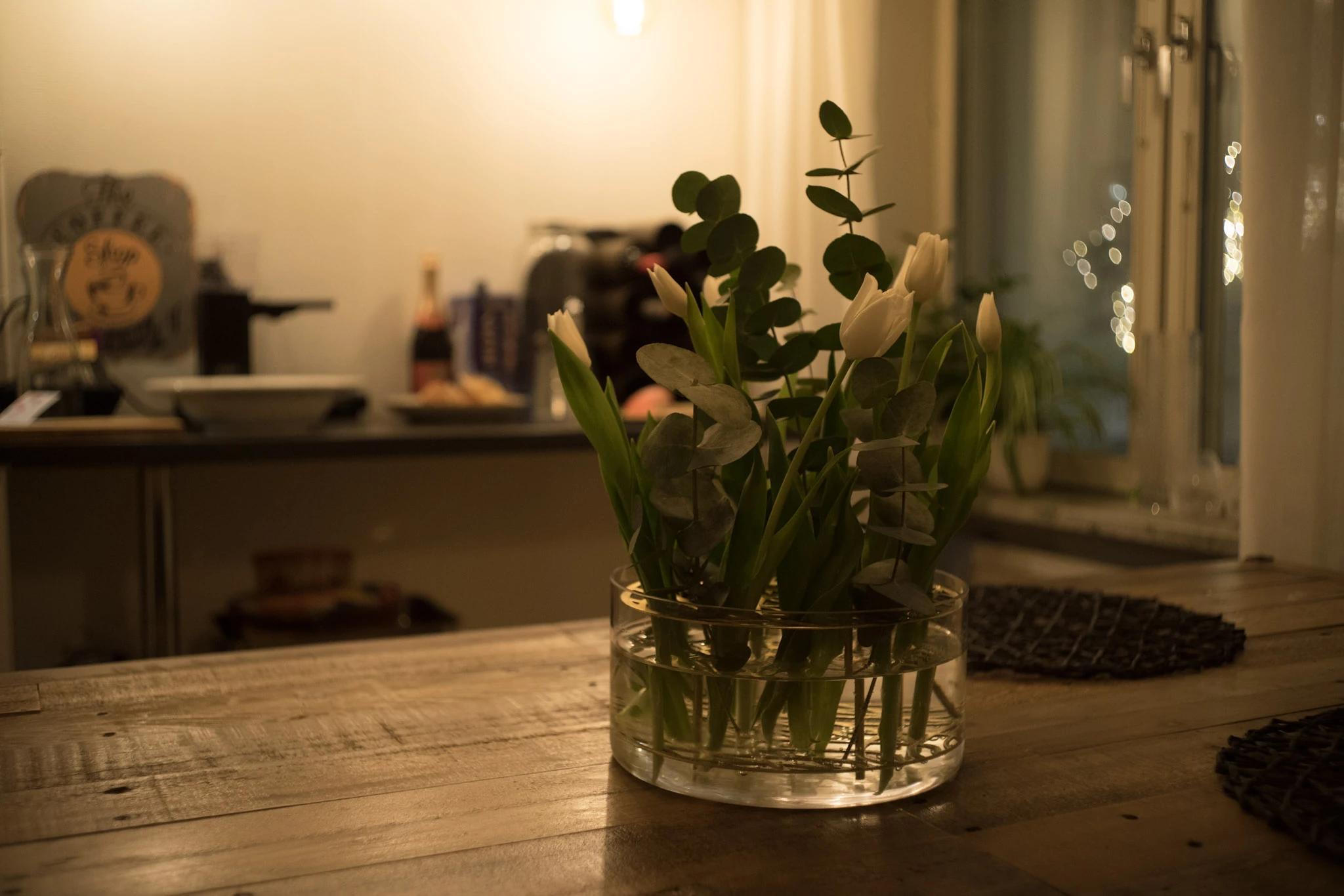 A vase of flowers on a kitchen table in warm light.