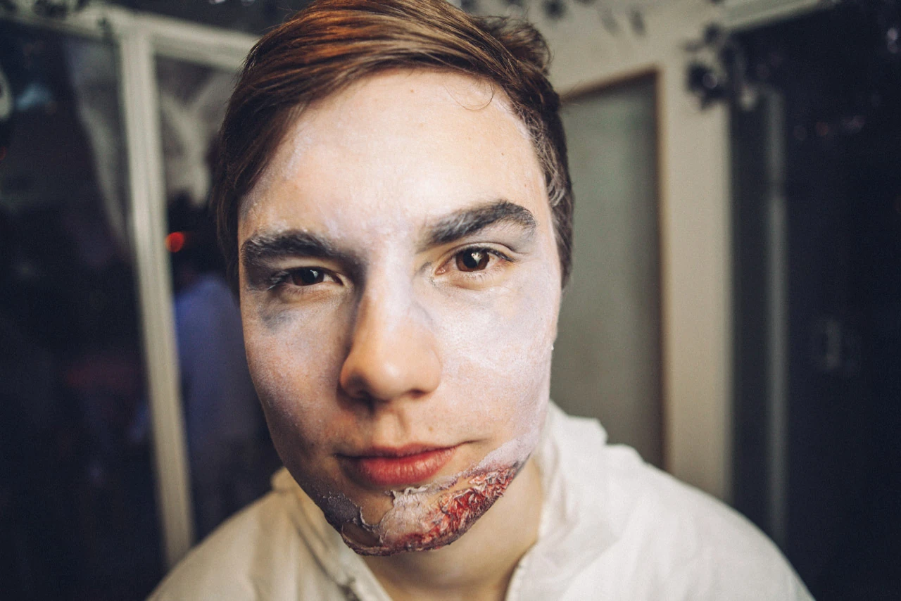 Närporträtt av en man med maskeratsmink kring munnen.