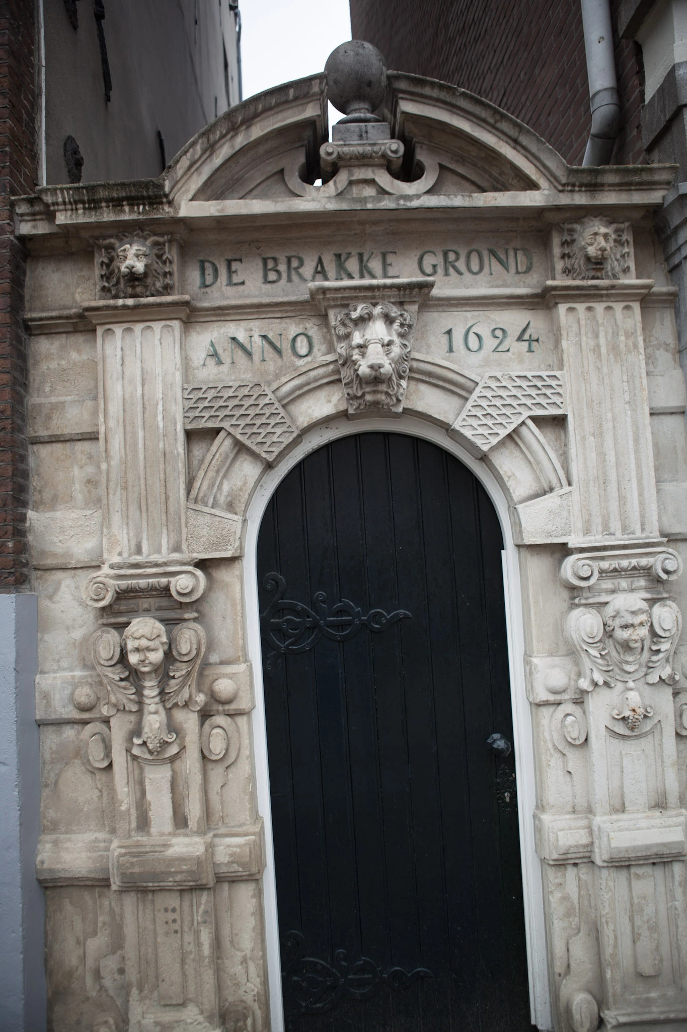 An ornate pale stone portal bearing the year 1624 above a dark arched door.