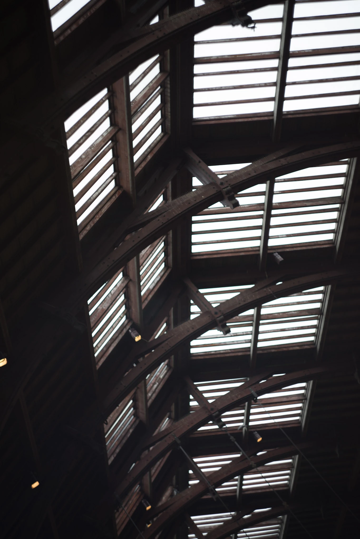 Light through glass between dark roof beams.