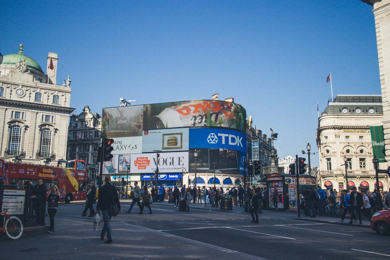 People and large billboards at a square in London.