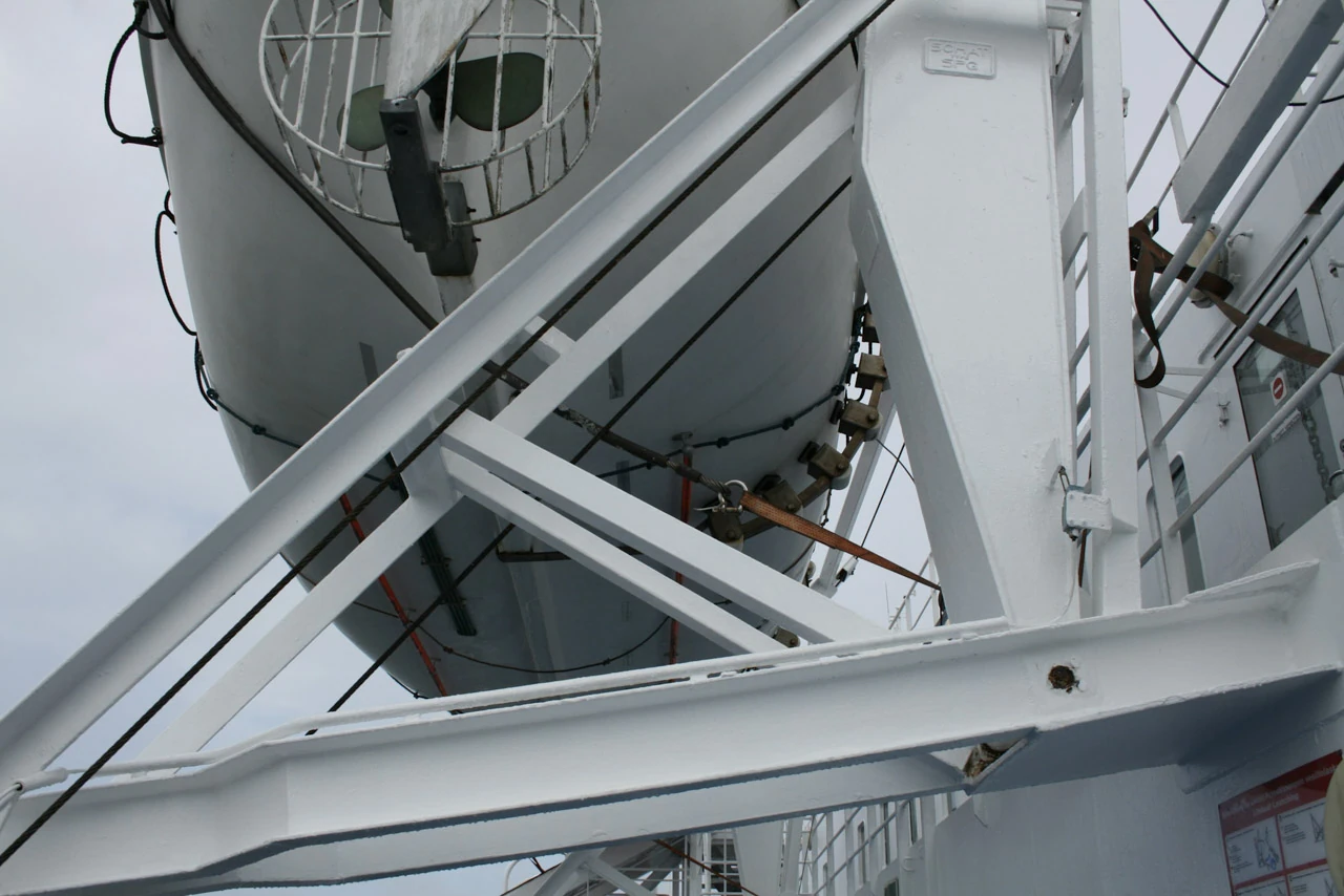 White railings and a lifeboat form intersecting lines along a ship.