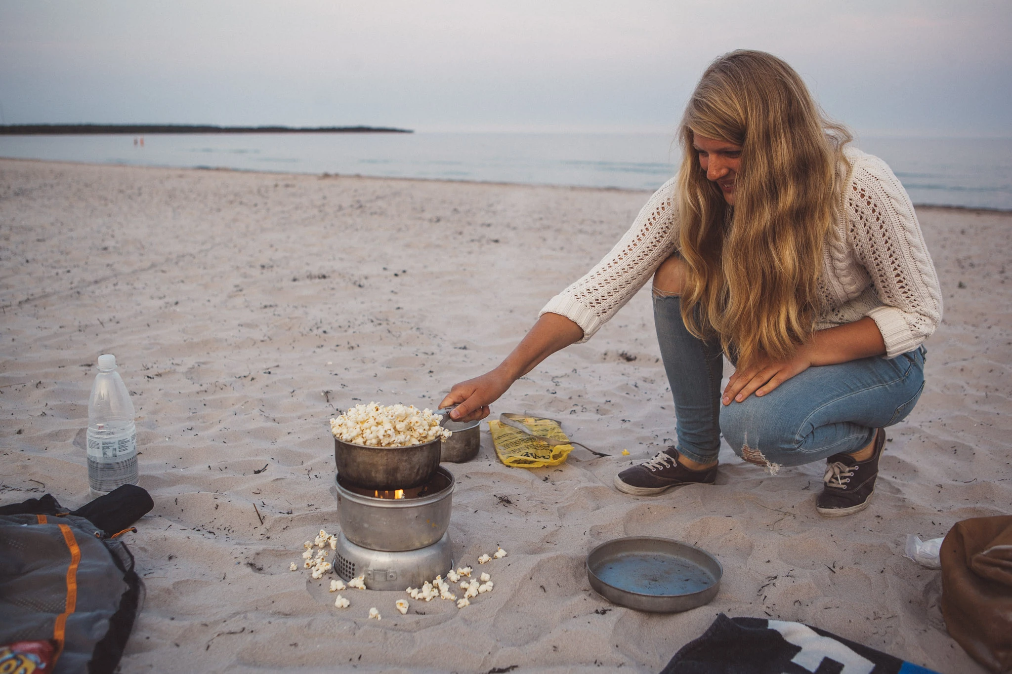 En person lagar mat på ett litet stormkök på stranden.
