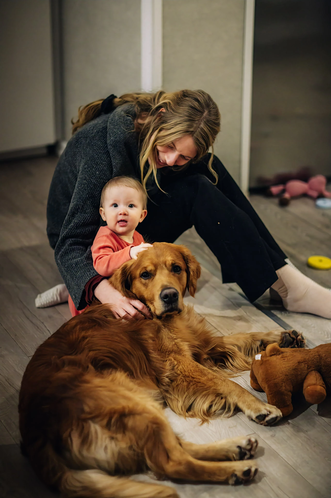 En kvinna, ett barn och en hund tillsammans på golvet i jultid.