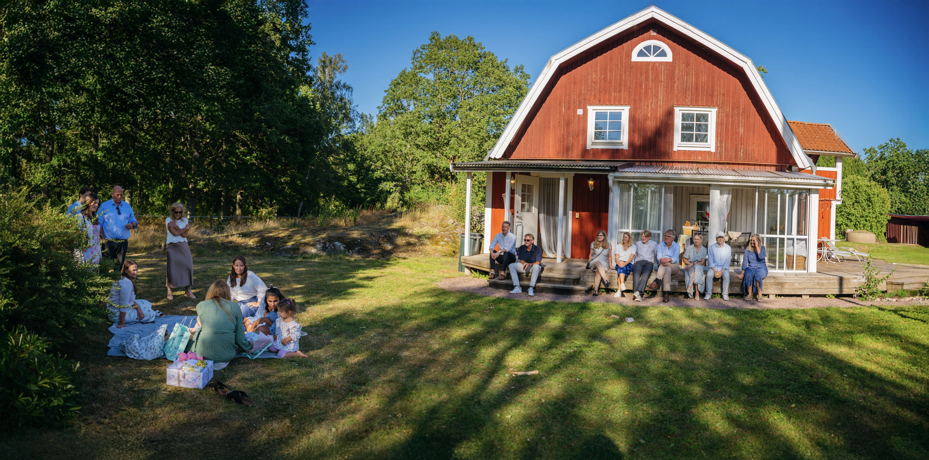 Ett familjefirande på gräsmattan framför ett rött hus.